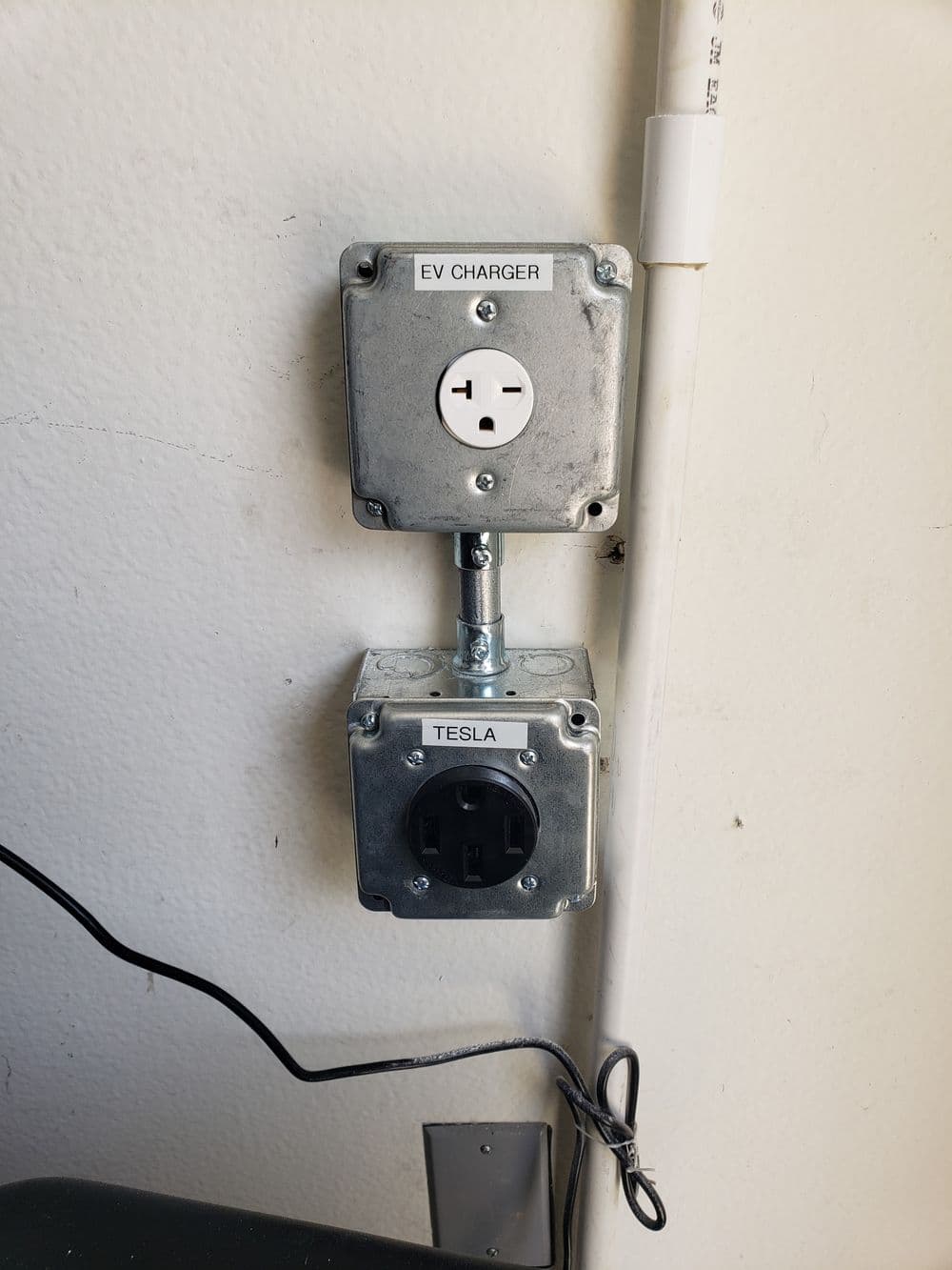 EV charger and Tesla charging outlet installed on a wall, showcasing electrical configurations.